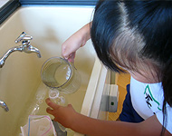 いろいろな形の容器をかさを調べて問題を作成している子ども